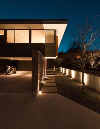Contemporary modern home exterior driveway at night with accent lighting