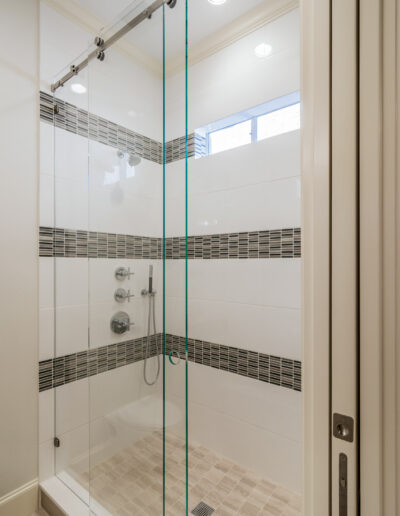 shower stall with accent tile, a small window, and rolling glass doors