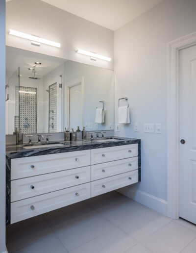 bathroom dual vanity with dark stone counters, wall-mounted light fixtures, and a large mirror