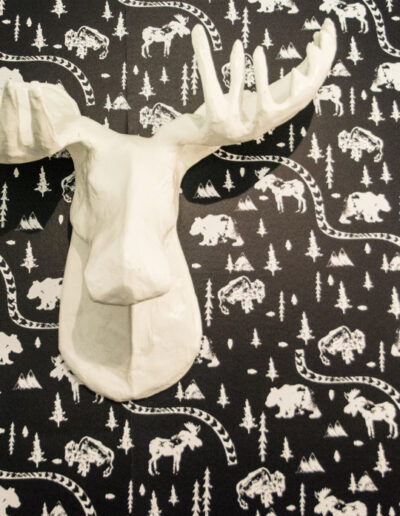 white faux moose head on black wallpaper