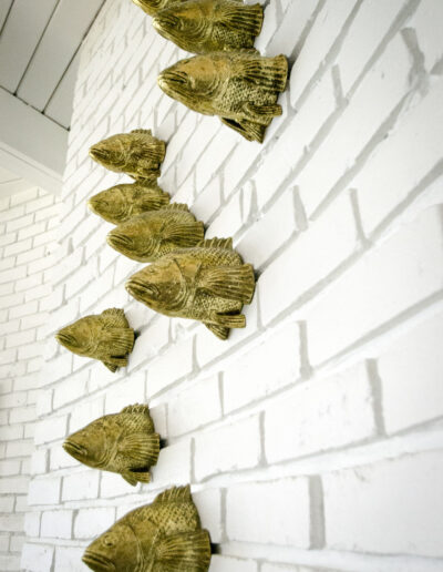 Gold fish head decor sticking out of white brick wall