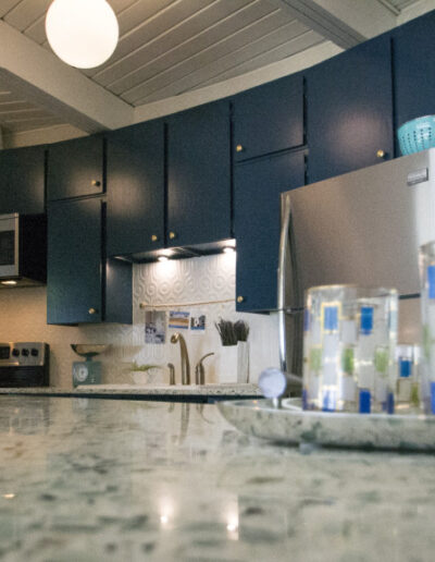 curved kitchen with granite countertops, rustic wood ceiling, mid-century modern fixtures, and blue cabinets