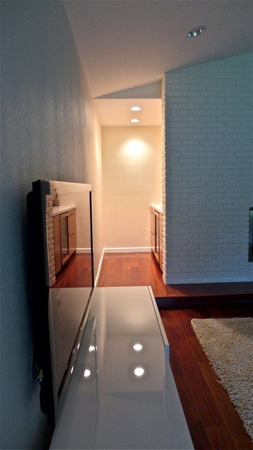 dimly lit room with wood hallway, white brick, and TV