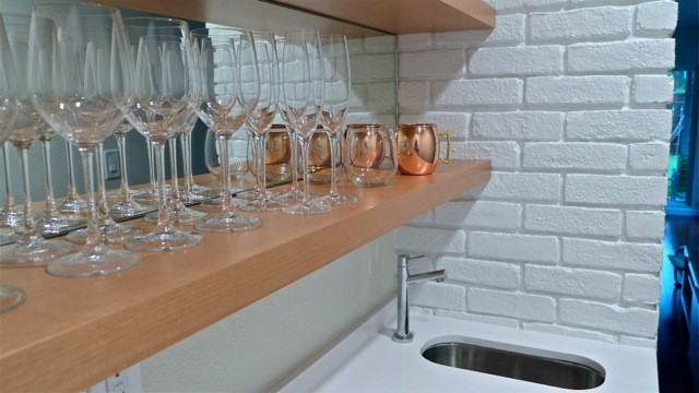 Wet bar with small sink, white brick, and built-in shelves