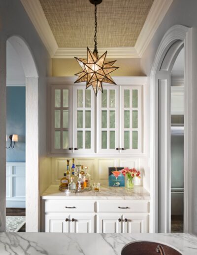 wet bar space with white cabinets, arched doorways and star chandelier