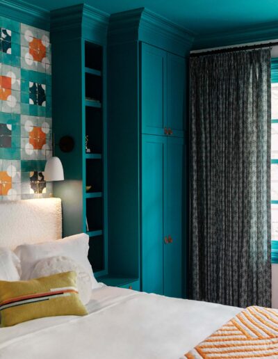 deep teal blue room where the cabinets, shelving, and ceiling are all the same color with teal artwork above the headboard