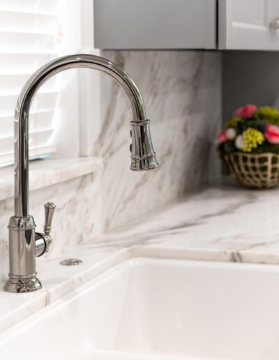 farmhouse sink in front of the kitchen window with silver gooseneck faucet