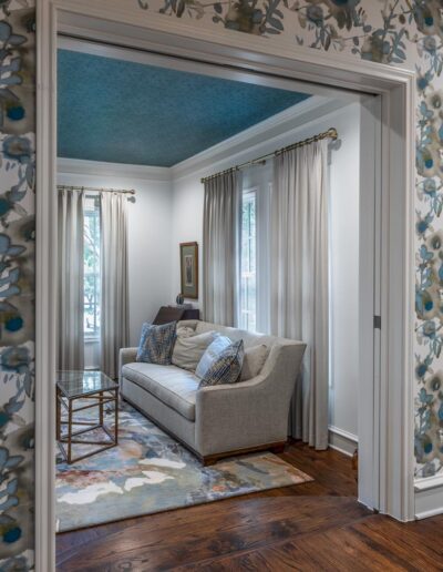 floral wallpapered dining room with a wide doorway with pocket doors leads down wooden steps to the living room