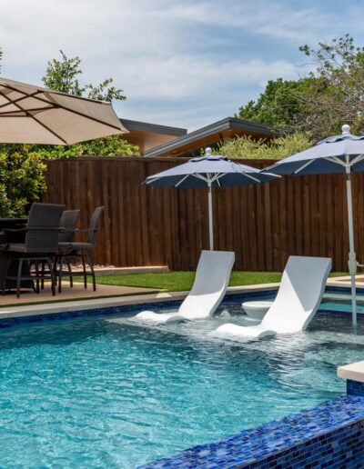 poolside lounge chairs with umbrellas and lounge chairs in the pool
