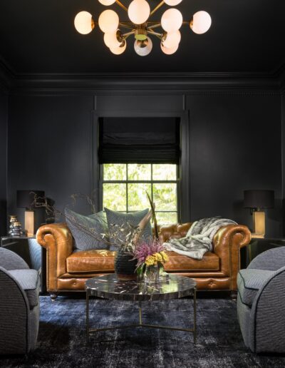 moody living room with dark walls, black curtains, gold glass ball chandelier, and beautiful furniture
