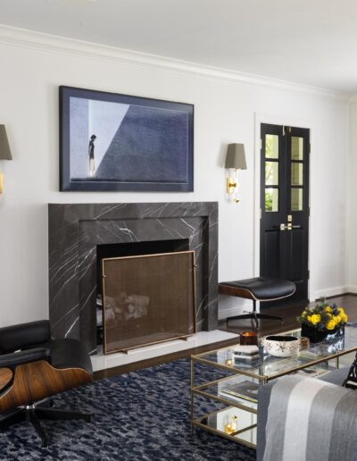 black stone fireplace in a white mid century modern style living room with wood floors and painted French doors