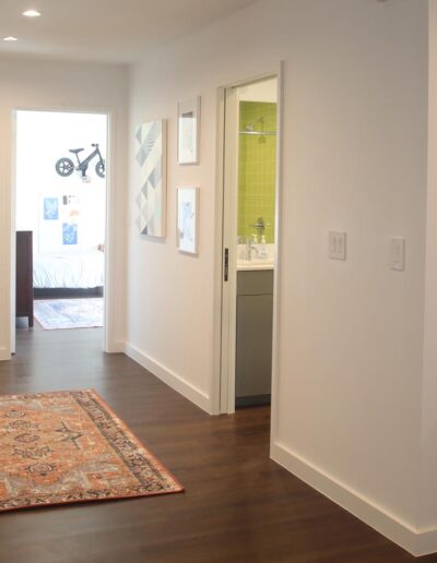 Interior hallway with flat white walls, clean, angular baseboards, and dark wood floors
