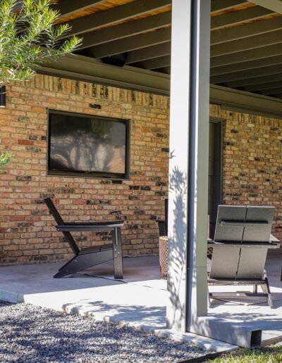 Covered paved outdoor patio with TV built into the brick wall and clean-line, contemporary gutters